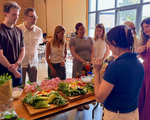 Marni demonstrating a recipe to a group gathered around the table